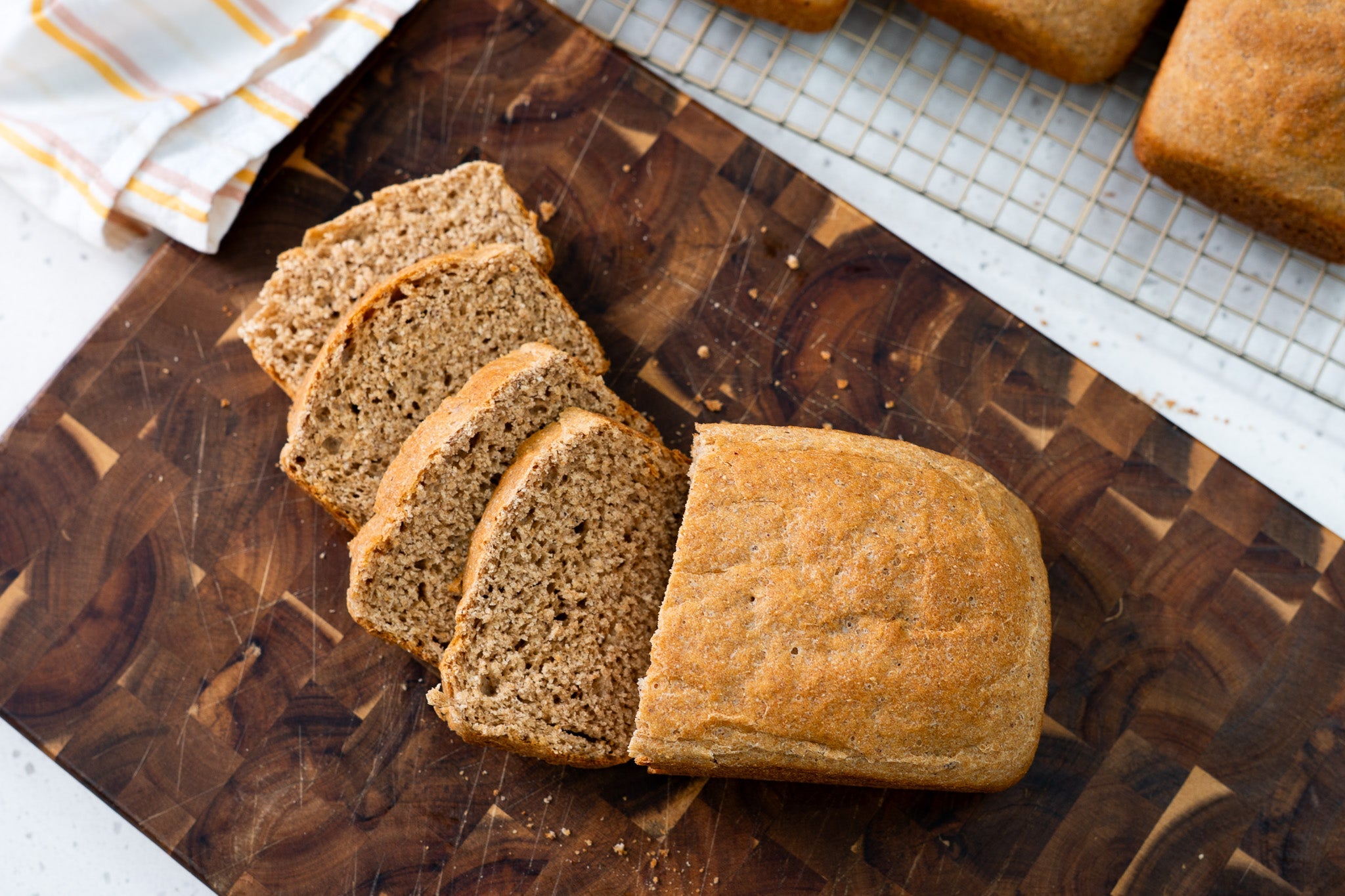 Freshly baked Ezekiel bread sliced on a wooden cutting board, showing a soft crumb and hearty texture.