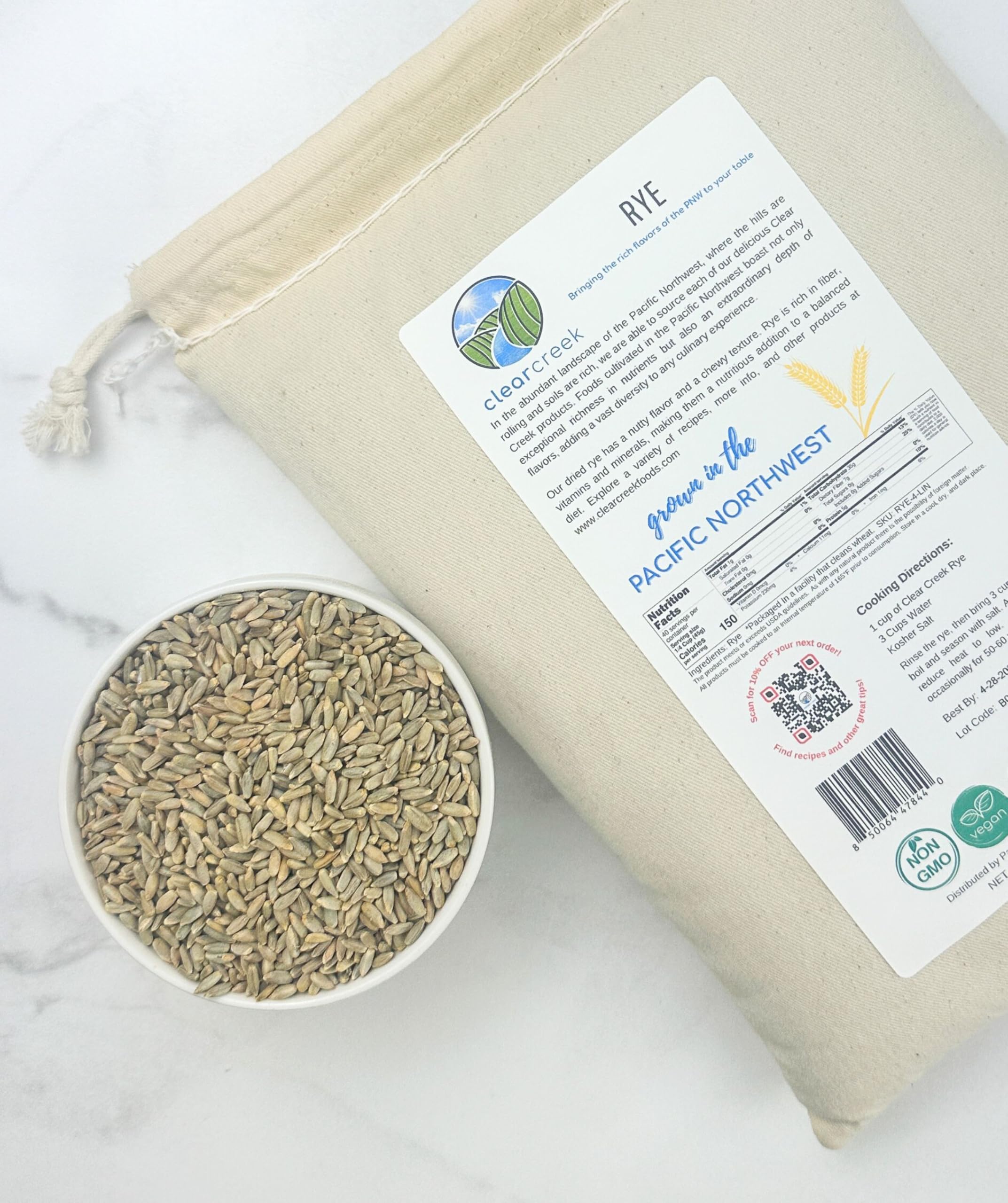 Clear Creek Rye canvas bag showing the back label and cooking directions beside a bowl of rye berries on a marble surface
