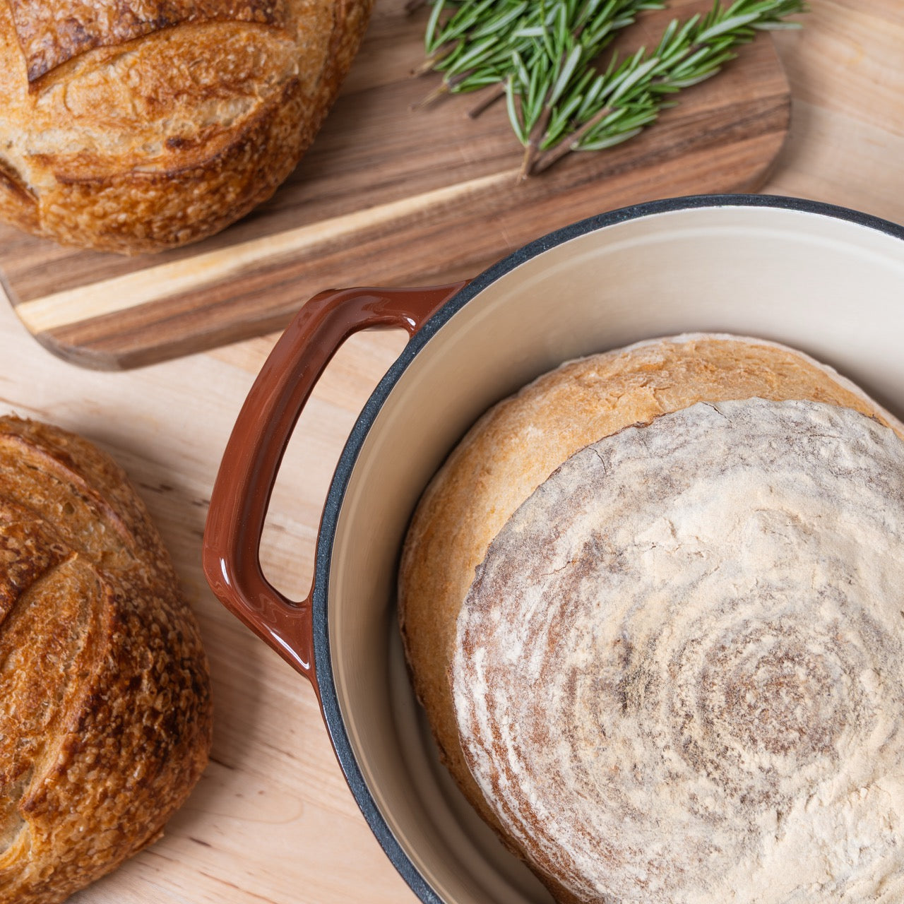 Loaves of bread and a ceramic cast Iron pot with bread on a wooden surface
