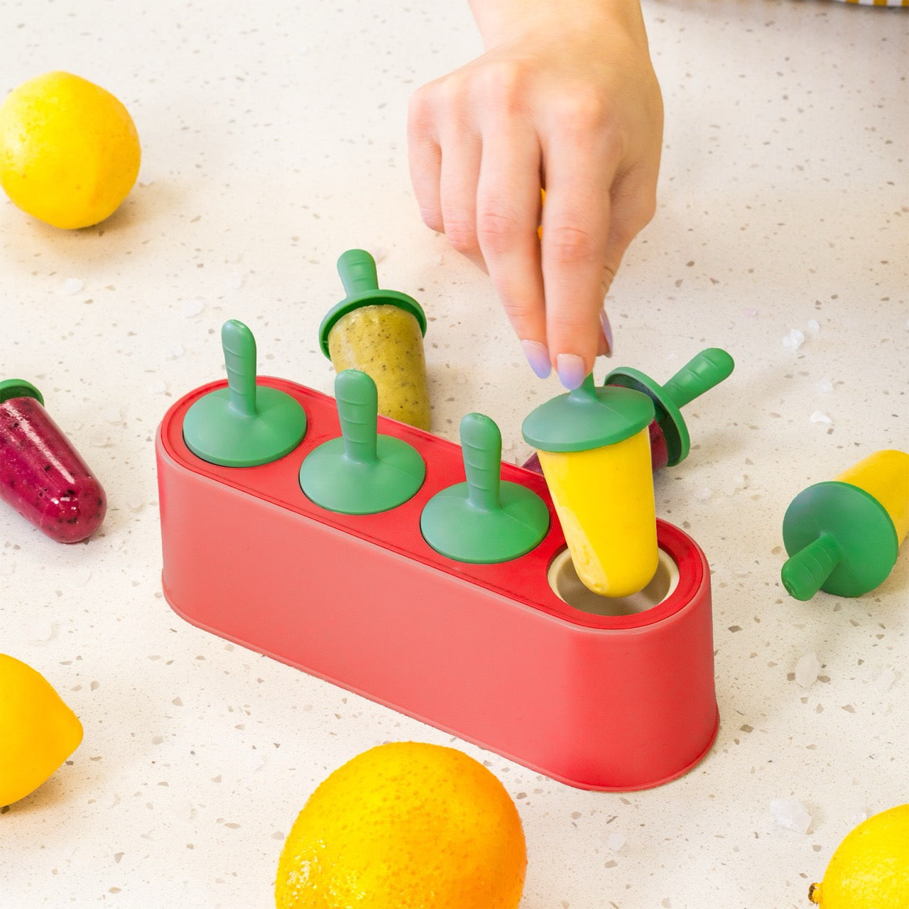 Popsicle mold with colorful popsicles on a speckled countertop.