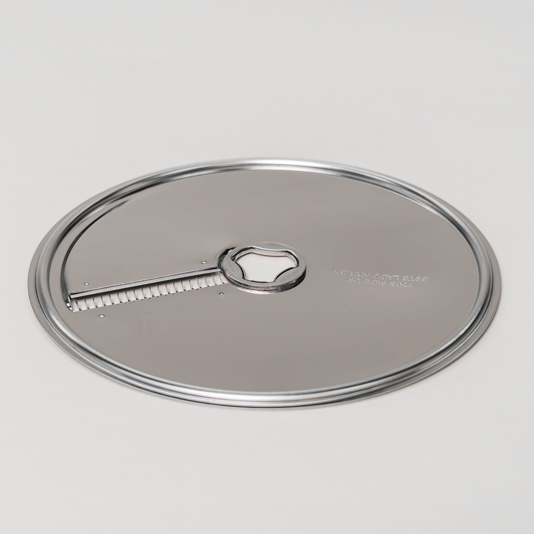 Stainless steel julienne disk for the NutriMill large slicer shredder attachment on a grey background