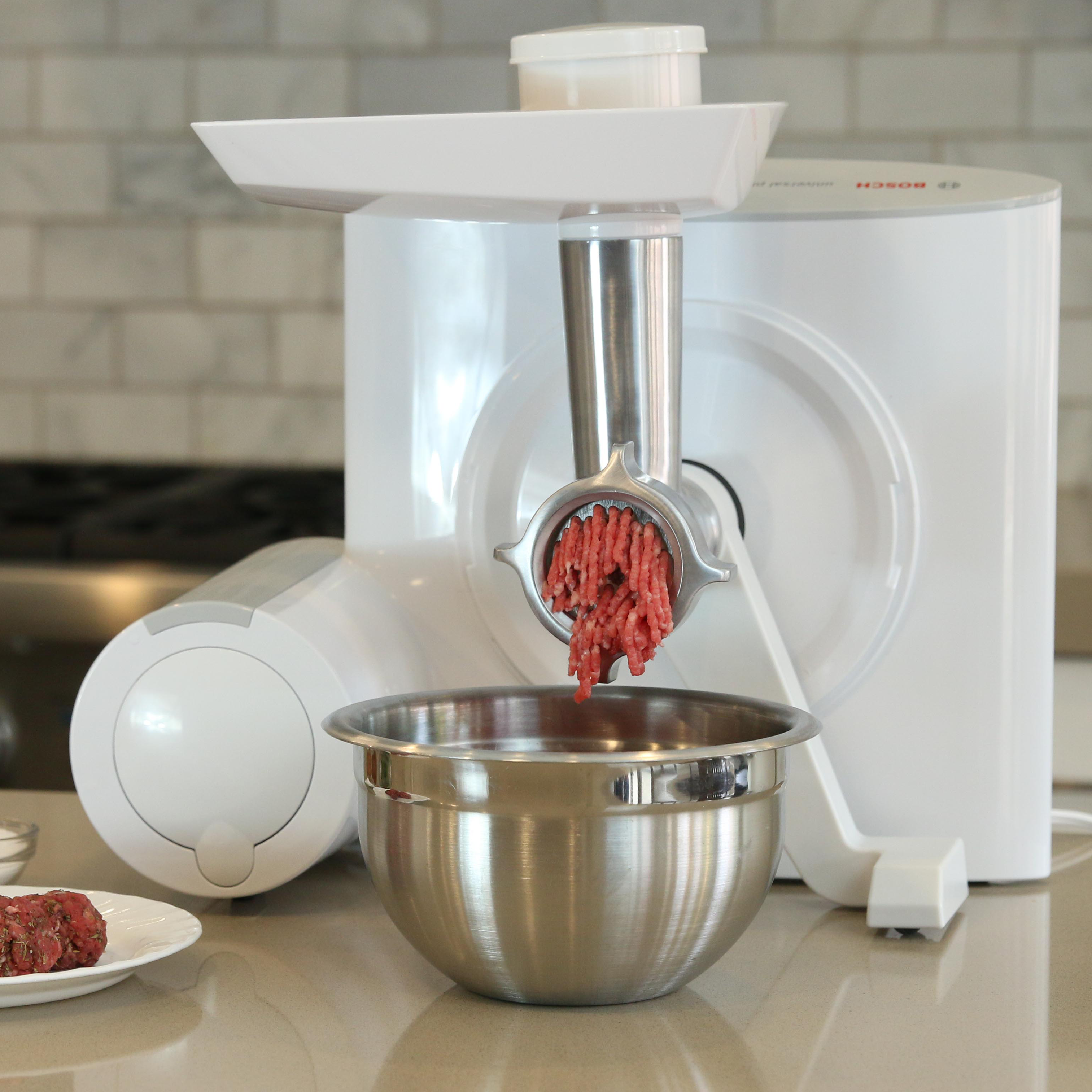 Bosch meat grinder grinding beef into a metal bowl on a grey kitchen counter