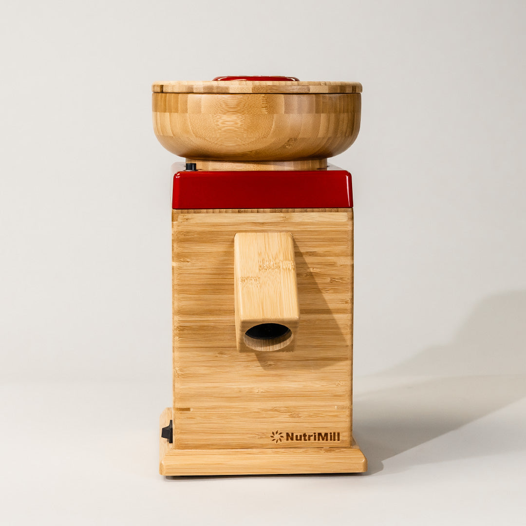 Bamboo grain mill with red trim standing on grey background