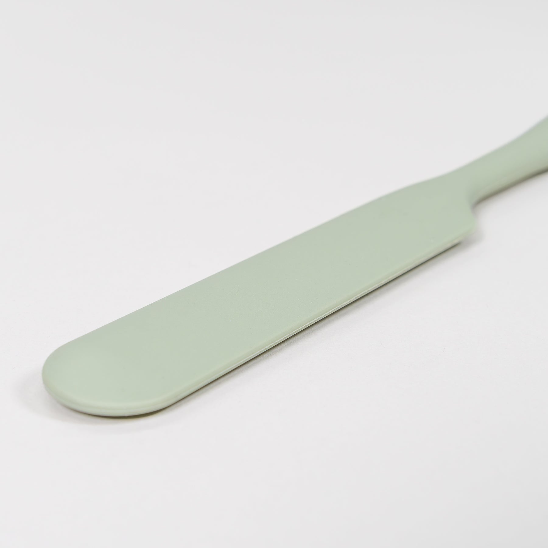 Mint green silicone scraper on a light gray background