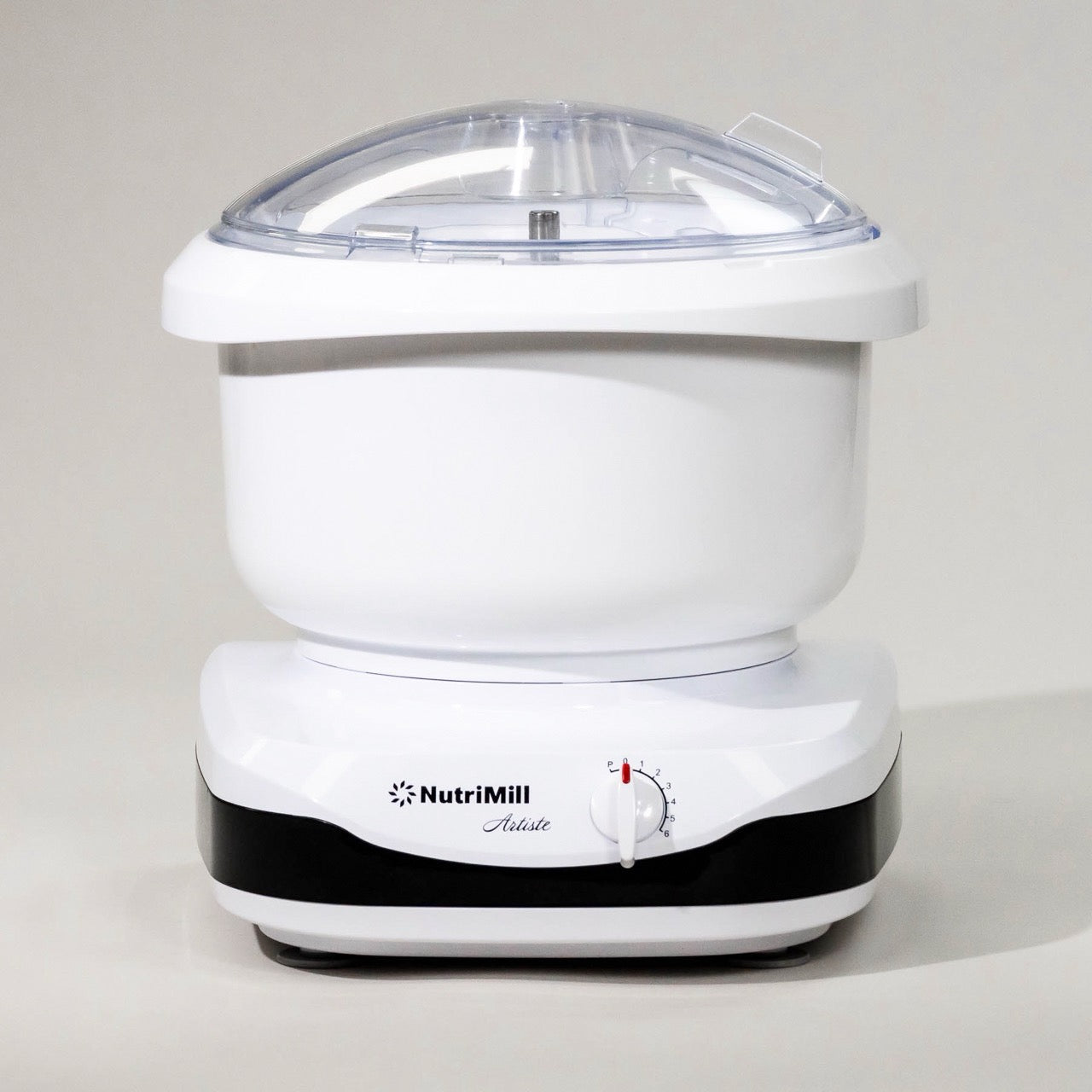 A white NutriMill Artiste Mixer with a clear lid, displaying the compact and bottom drive design of the appliance.