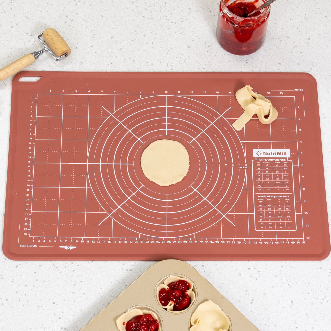 Baking mat with kitchen tools and ingredients on a white surface