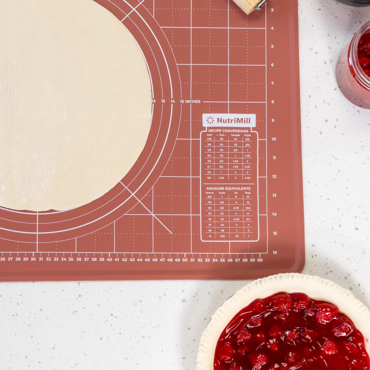 Baking mat with measurement markings next to a pie crust and jar of filling.