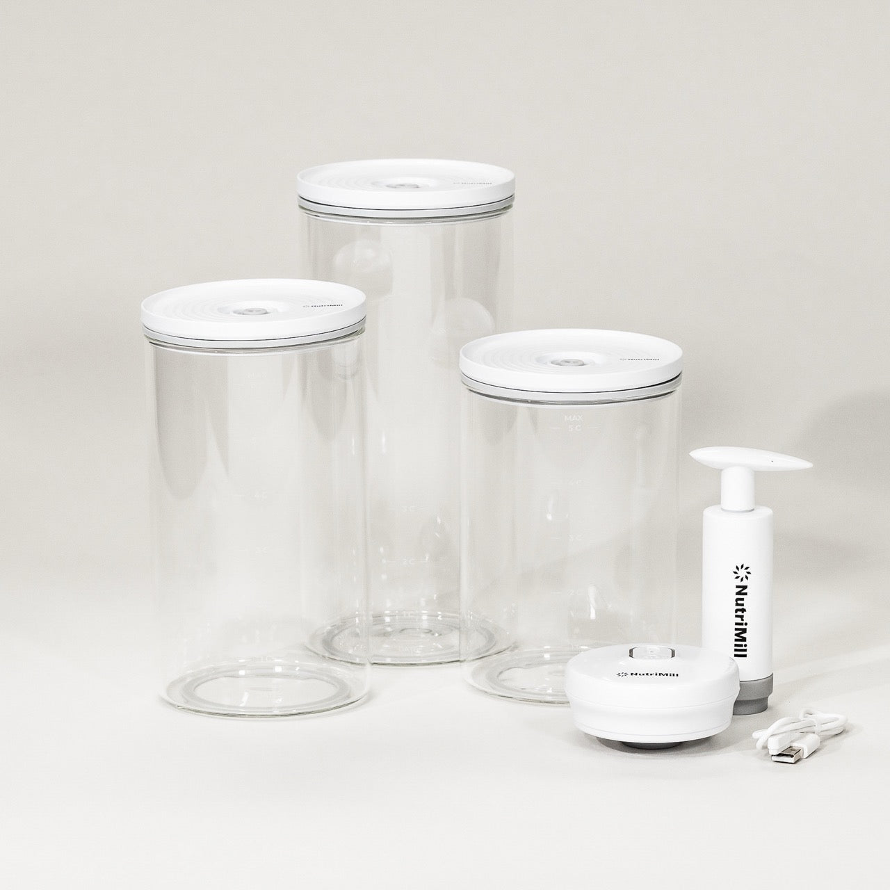 A set of three clear glass vacuum seal containers with white lids and a white vacuum pump, displayed against a neutral background.