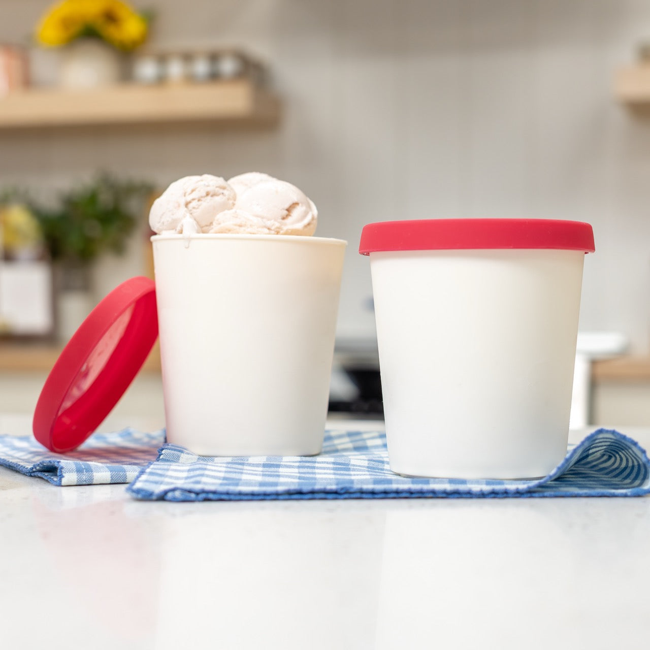 Two white containers with red lids on a kitchen counter