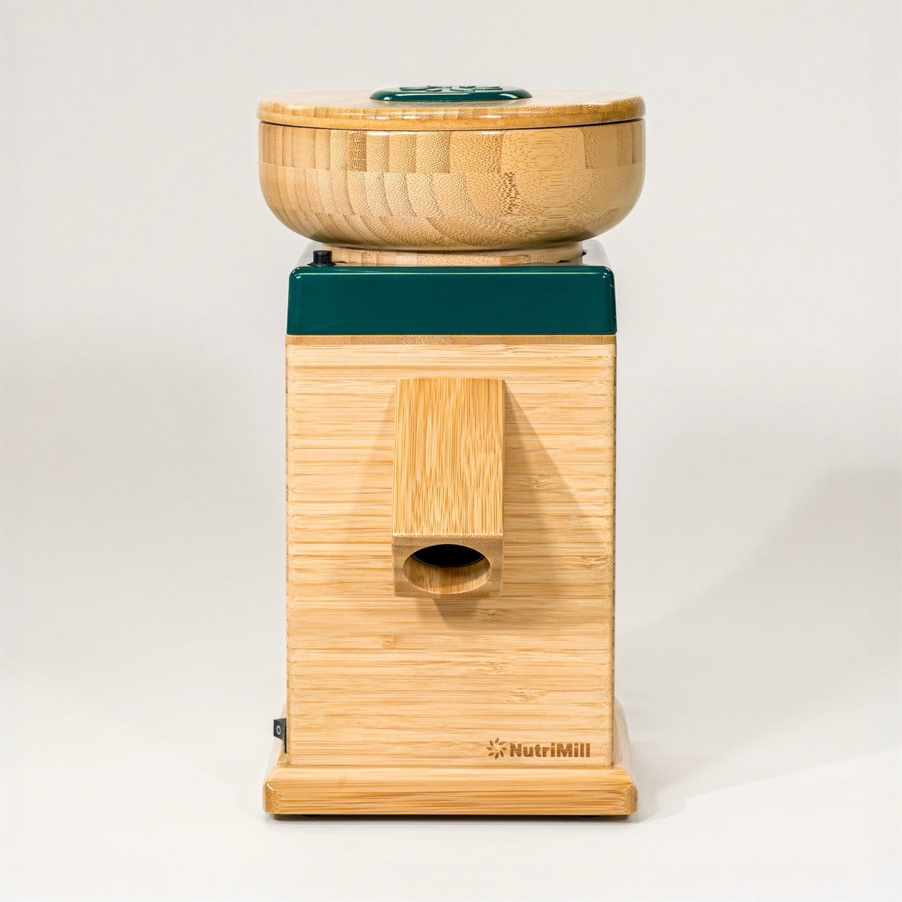 A NutriMill Harvest grain mill in forest green color, made of bamboo with a corundum milling stone, countertop size.