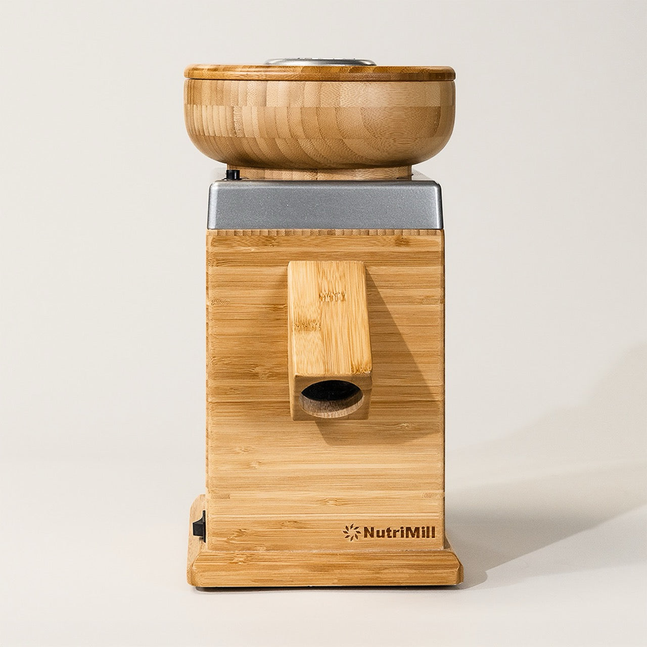 A silver Harvest Grain Mill by NutriMill, featuring a bamboo body with a wooden bowl on top, designed for grinding wheat and other grains.