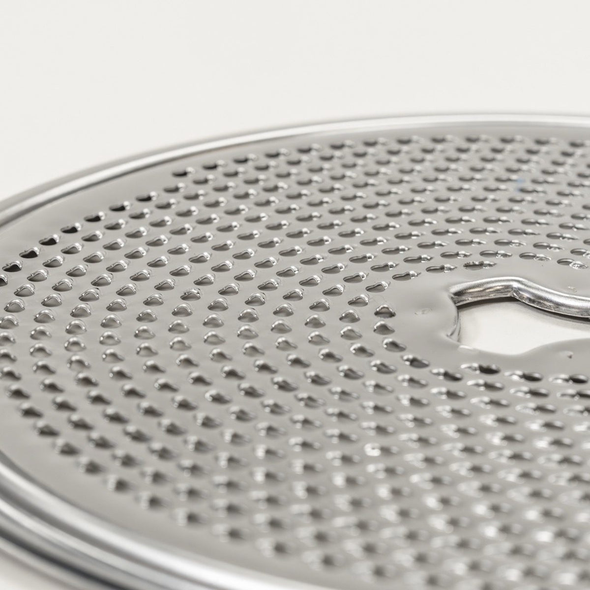 Close-up of the stainless steel fine grating disk for the NutriMill Large Slicer Shredder