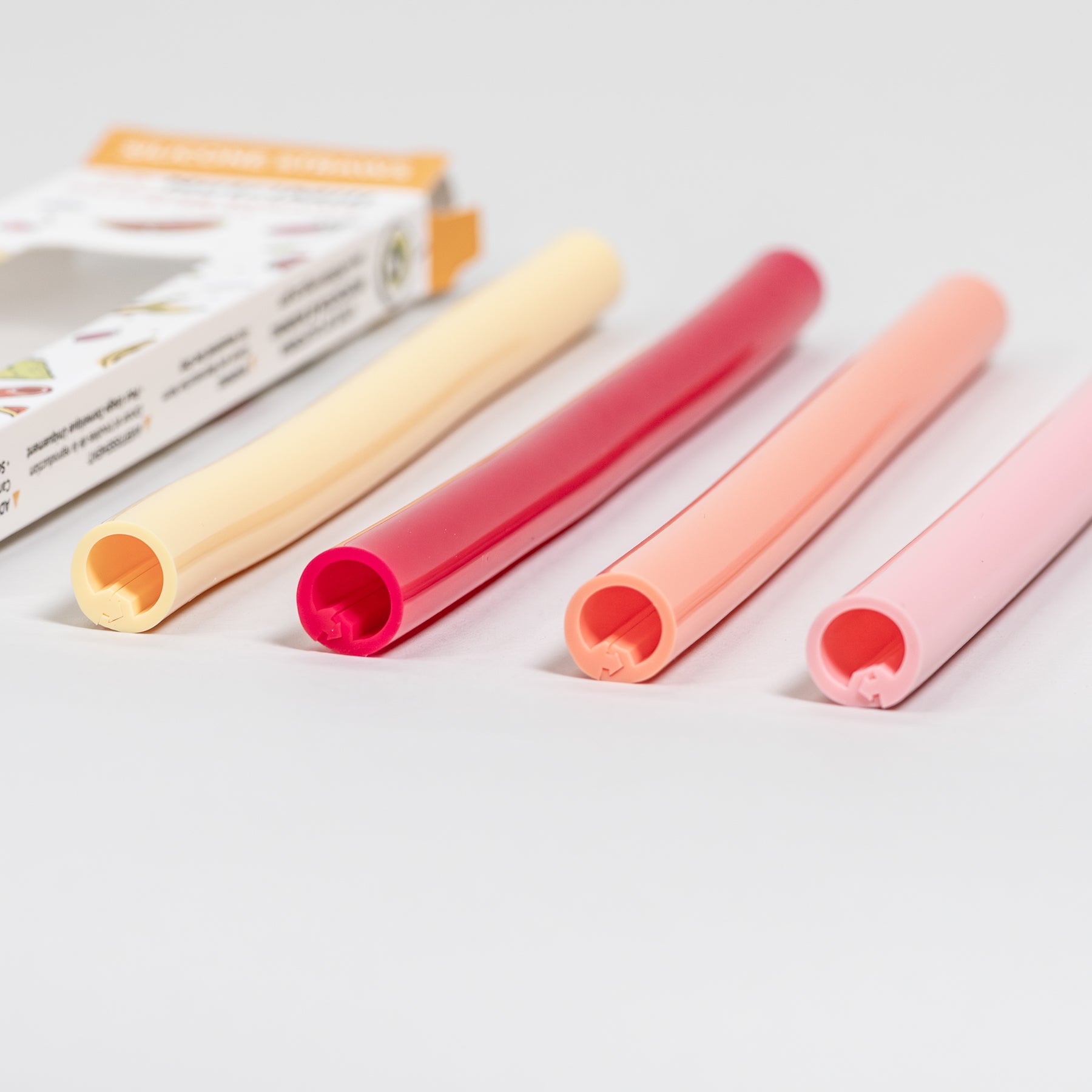 Set of colorful straws on a white background with a package in the corner.