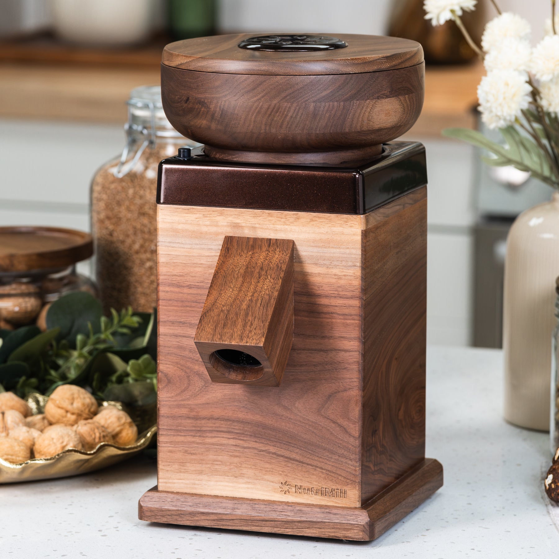 NutriMill Harvest Walnut grain mill with harvest logo and cocoa-colored trim on white counter with kitchen in background