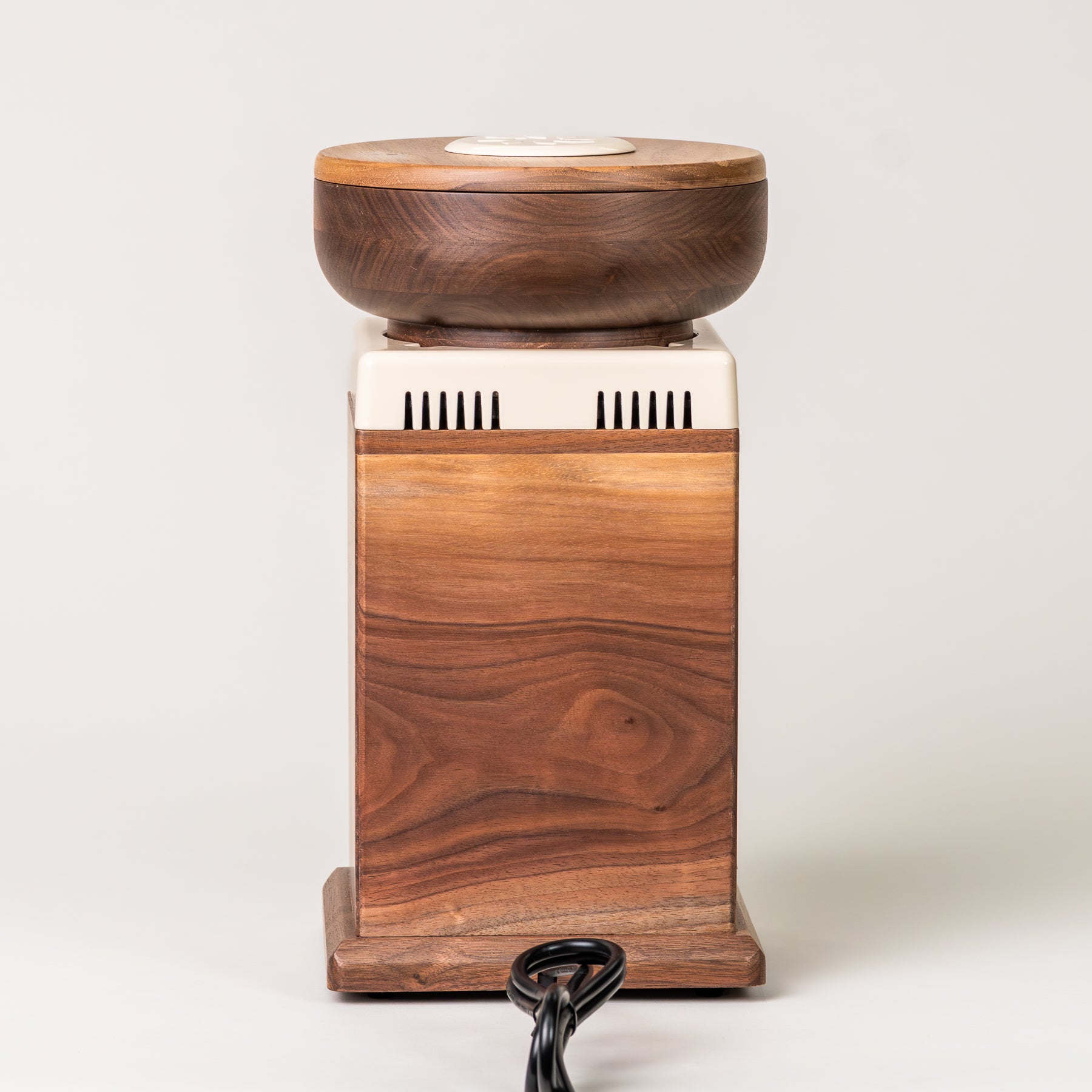 Behind angle of NutriMill harvest walnut grain mill with cream-colored trim on grey background