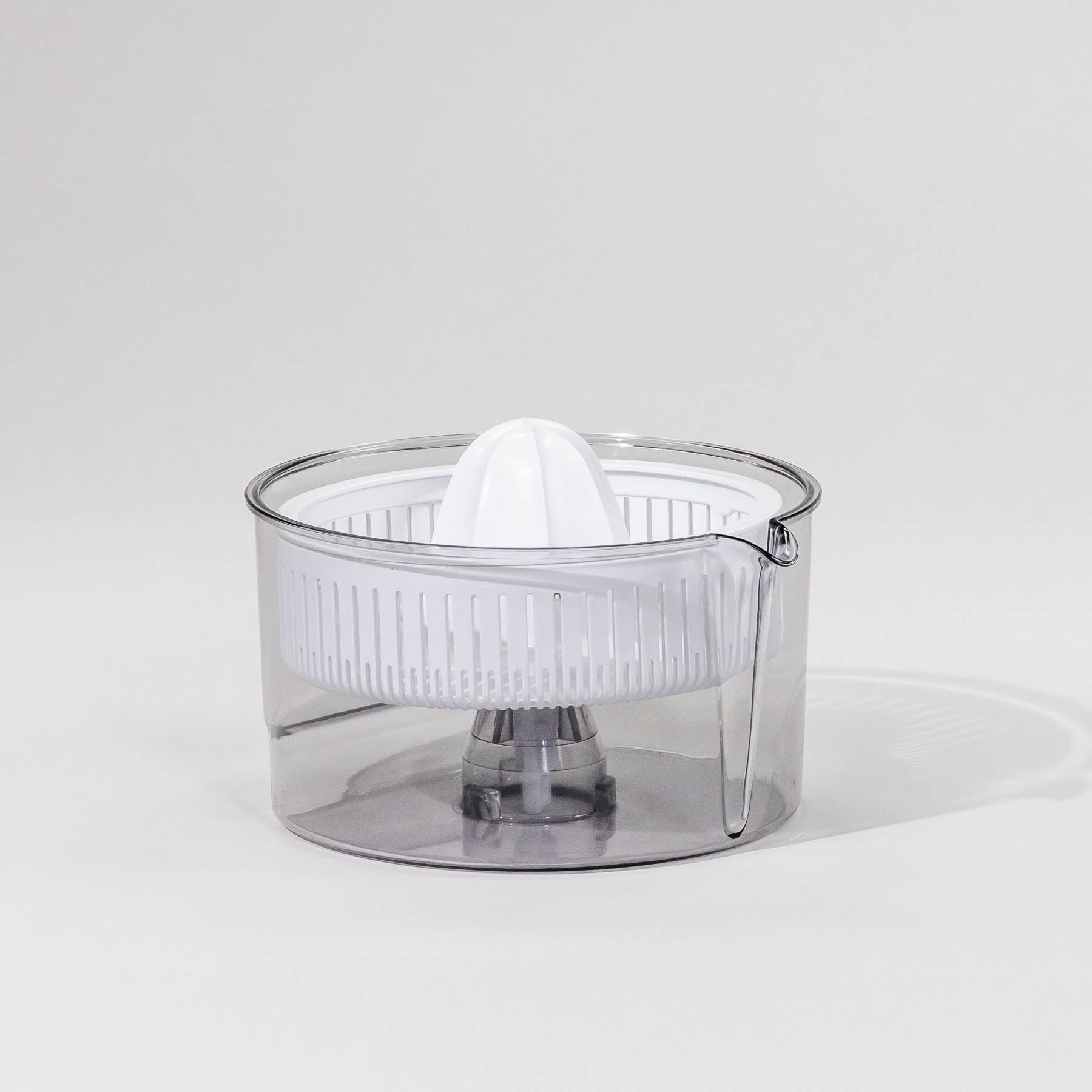 A clear citrus juicer attachment with a white juicer basket and a spout, designed to attach to a mixer.
