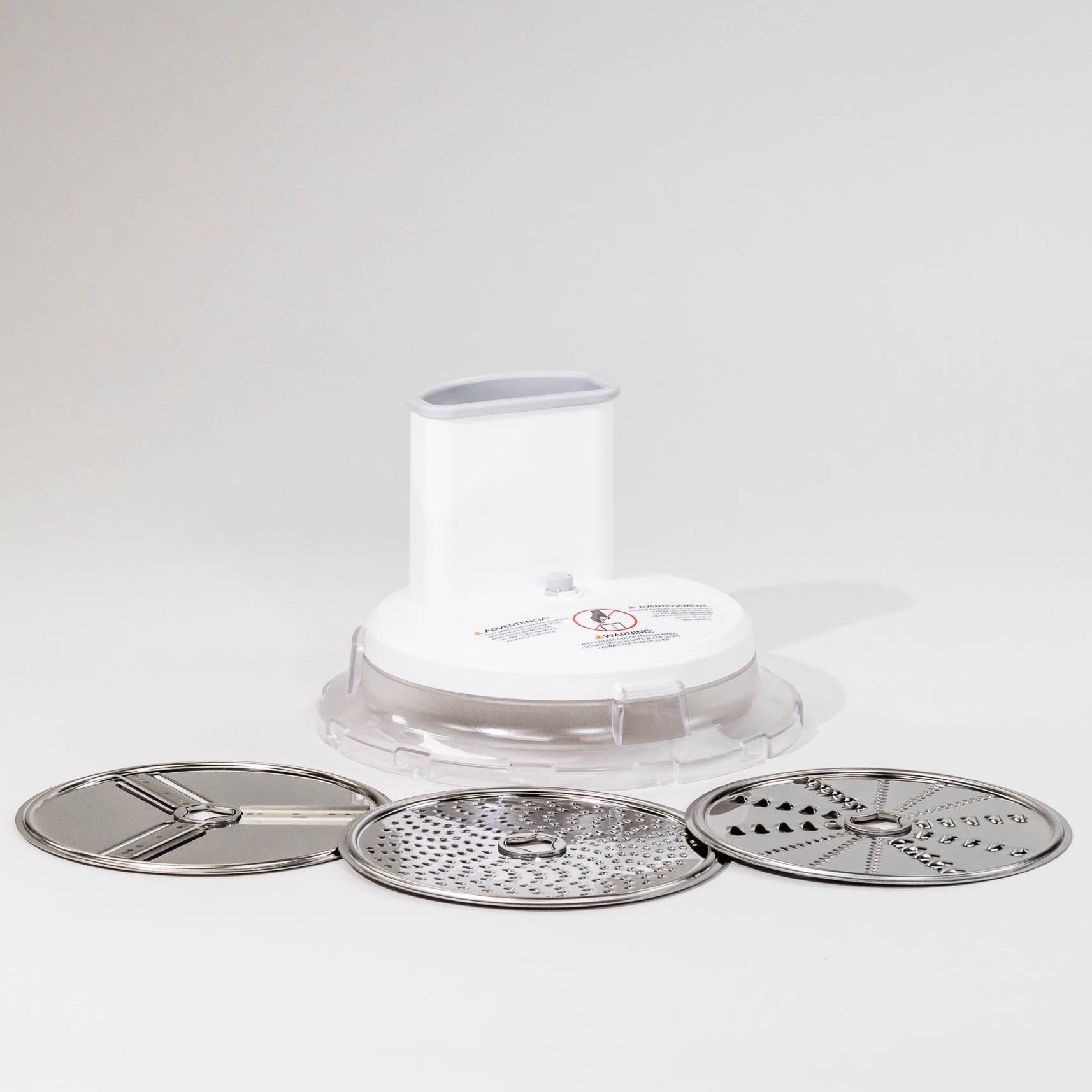 A white food slicer shredder attachment with three interchangeable stainless steel blades, displayed on a light background.