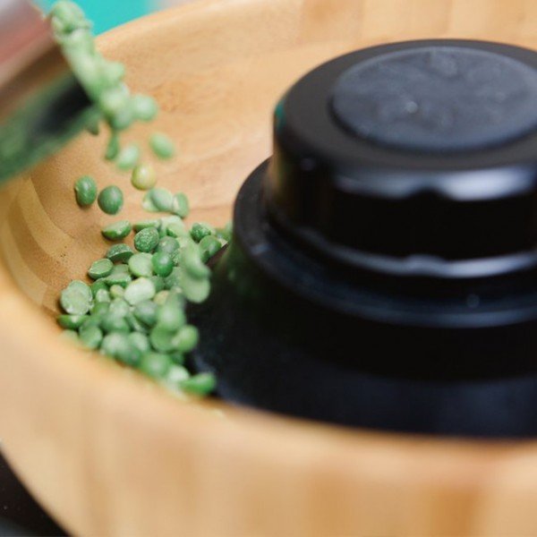 green lentils poured into NutriMill Harvest home grain mill hopper