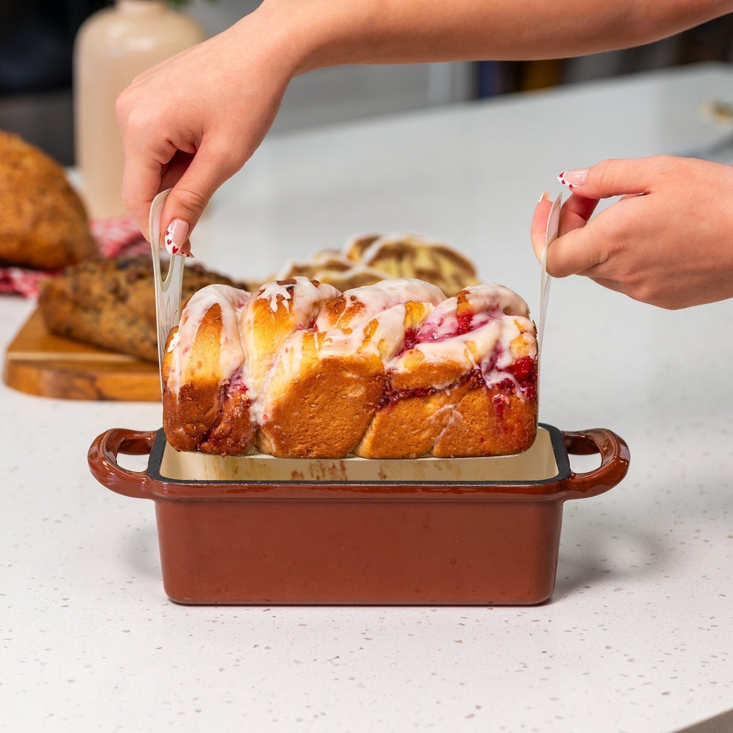 dessert bread being lifted out of the nutrimill cast iron bread pan with the nutrimill silicone bread pan sling