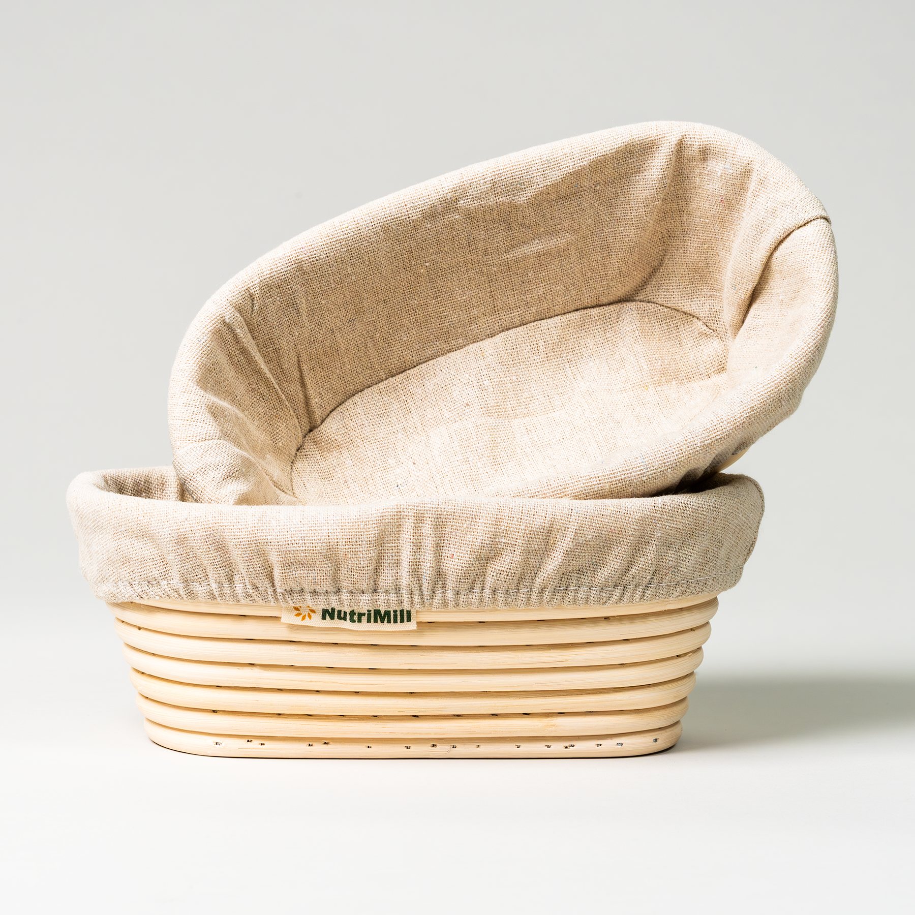 One NutriMill banneton basket sitting in the other on a grey background