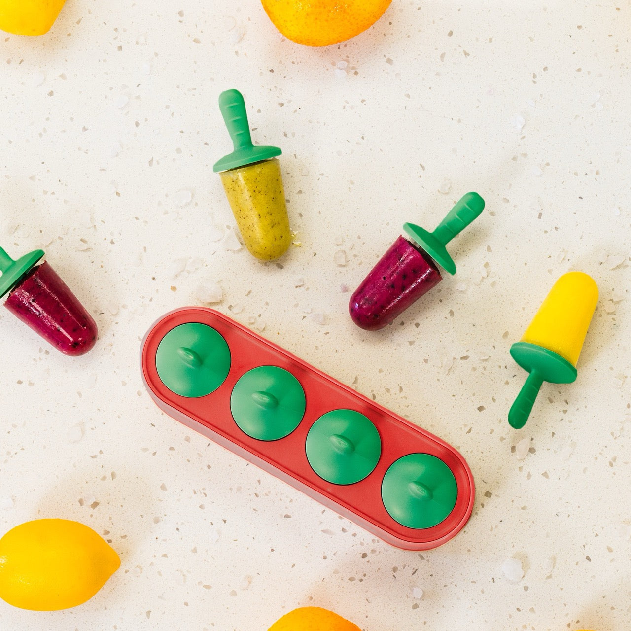 Colorful popsicles with green sticks on a white surface