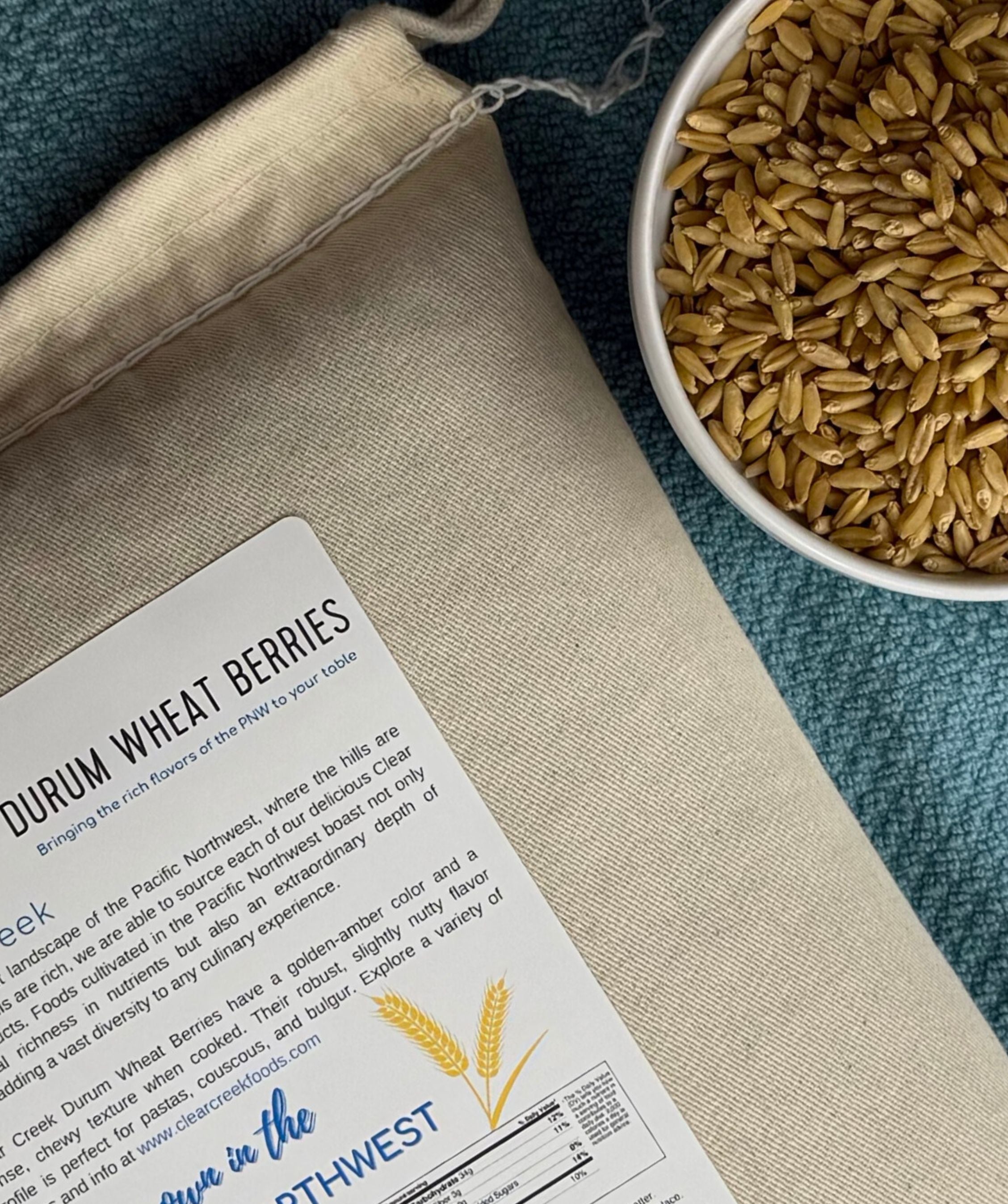 Clear Creek Durum Wheat Berries canvas bag beside a bowl of durum wheat berries