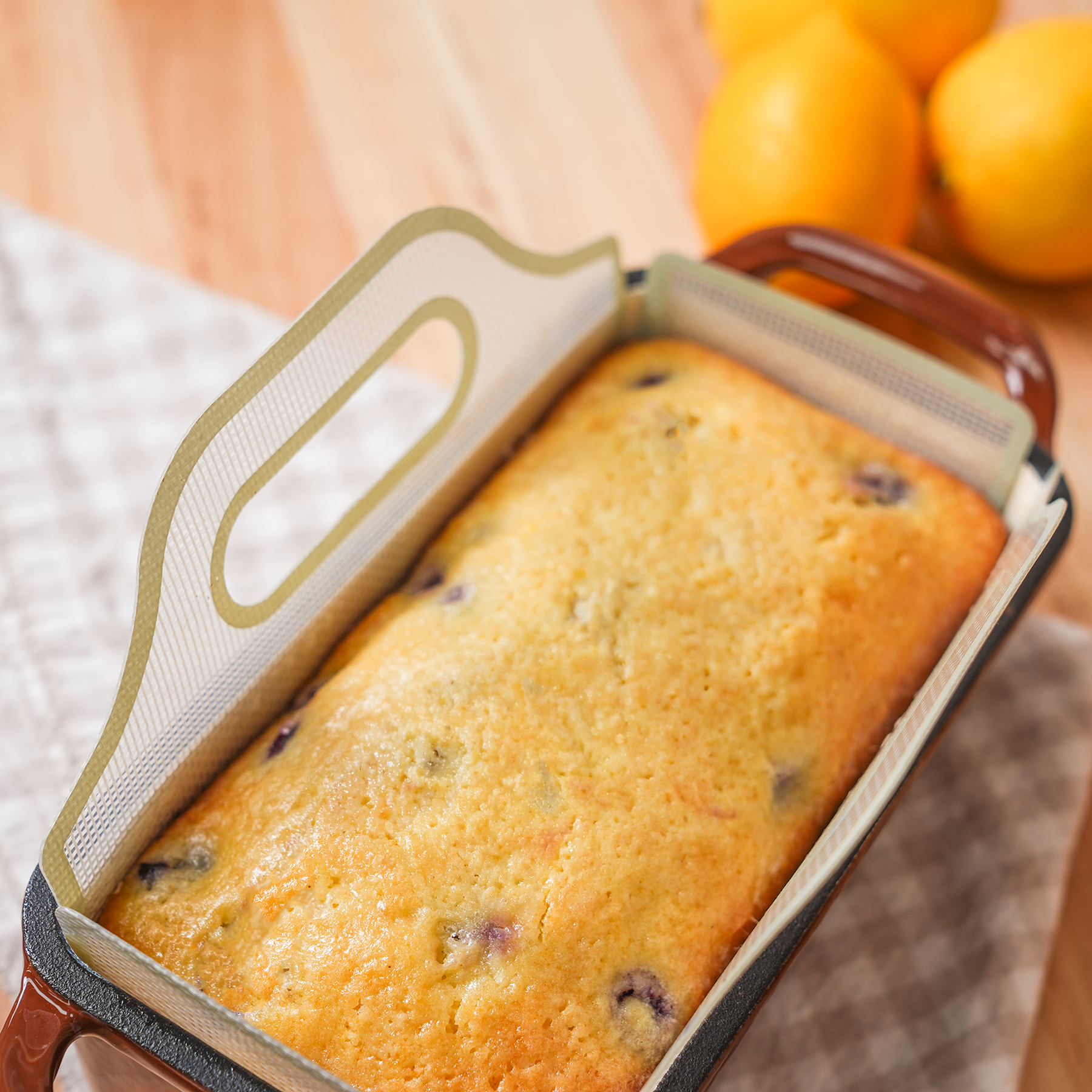 Overhead view of a lemon blueberry loaf in a ceramic bread pan with a parchment sling