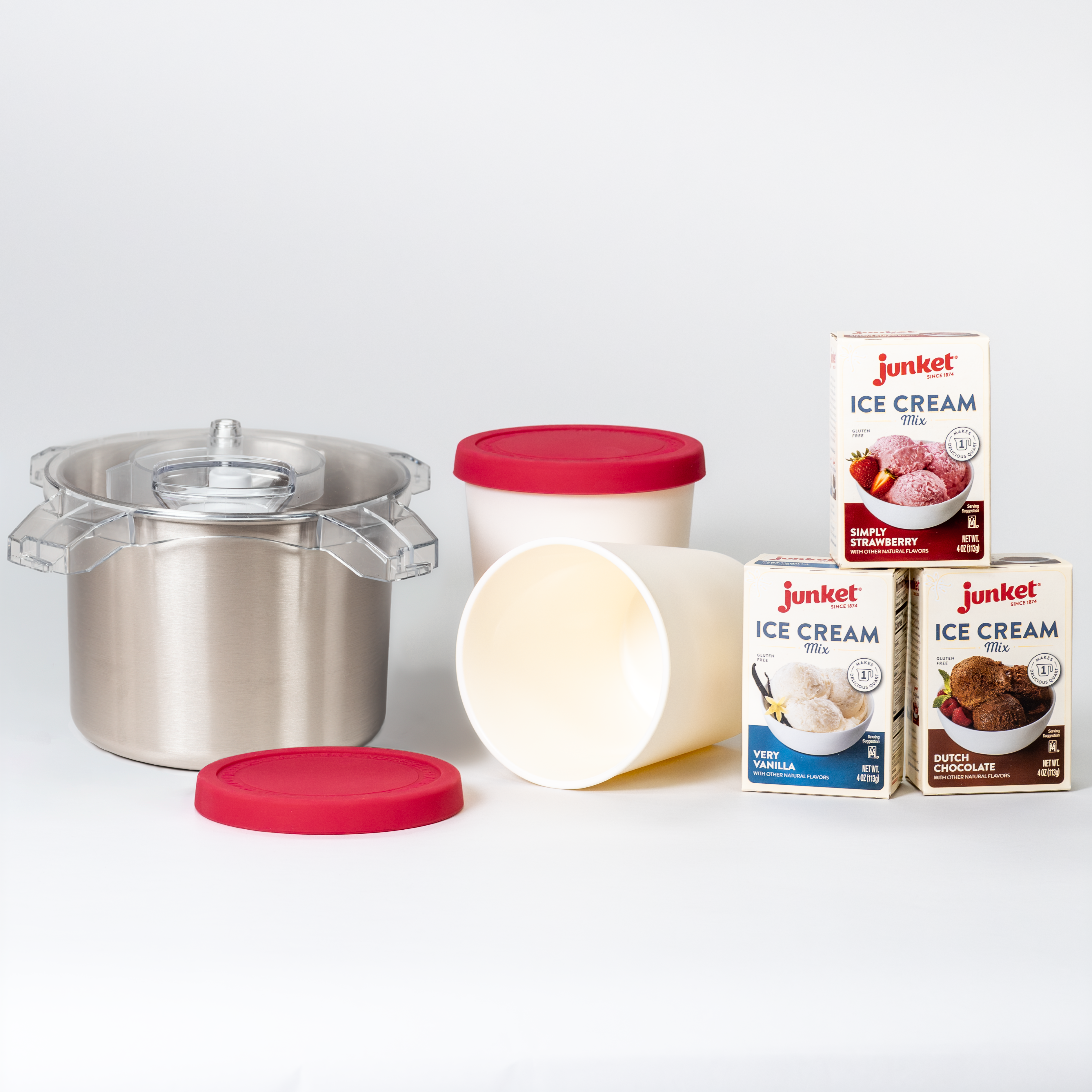 NutriMill Artiste ice cream maker freezer bowl with storage containers and Junket ice cream mix boxes in strawberry, vanilla, and chocolate on a white background