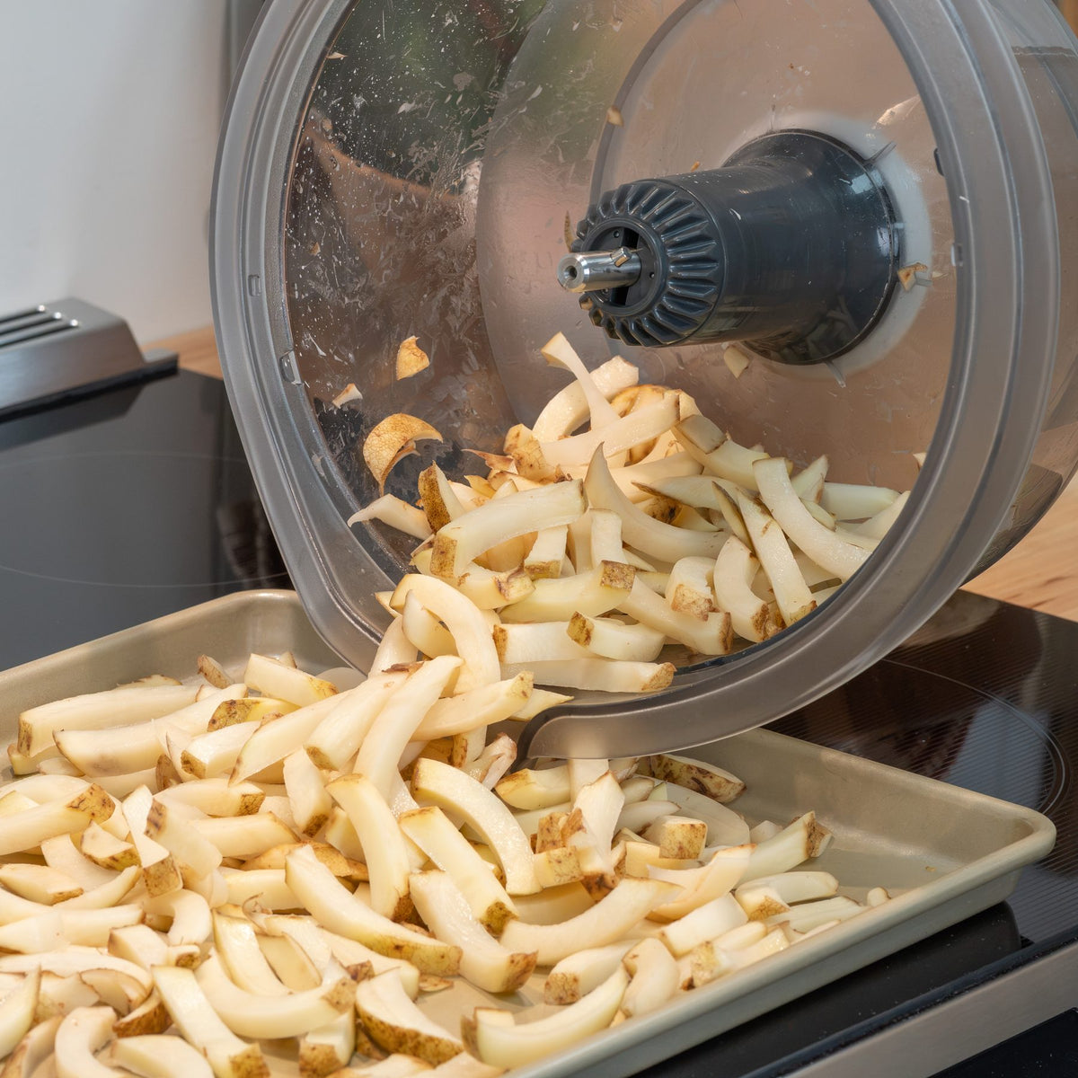 Fresh-cut potato fries made with the French Fry Disk pouring from a clear mixing bowl onto a baking sheet