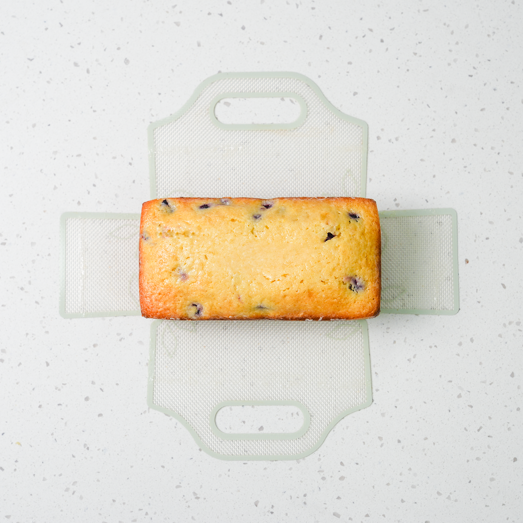 Overhead view of a blueberry lemon loaf on an unfolded silicone baking sling