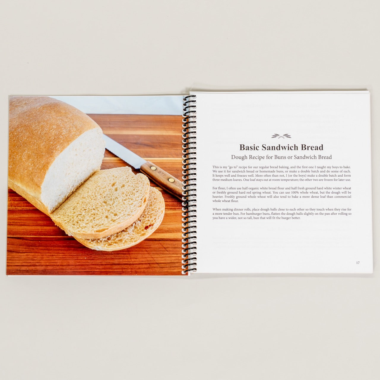 Cookbook open to a page about making basic sandwich bread on a wooden cutting board.