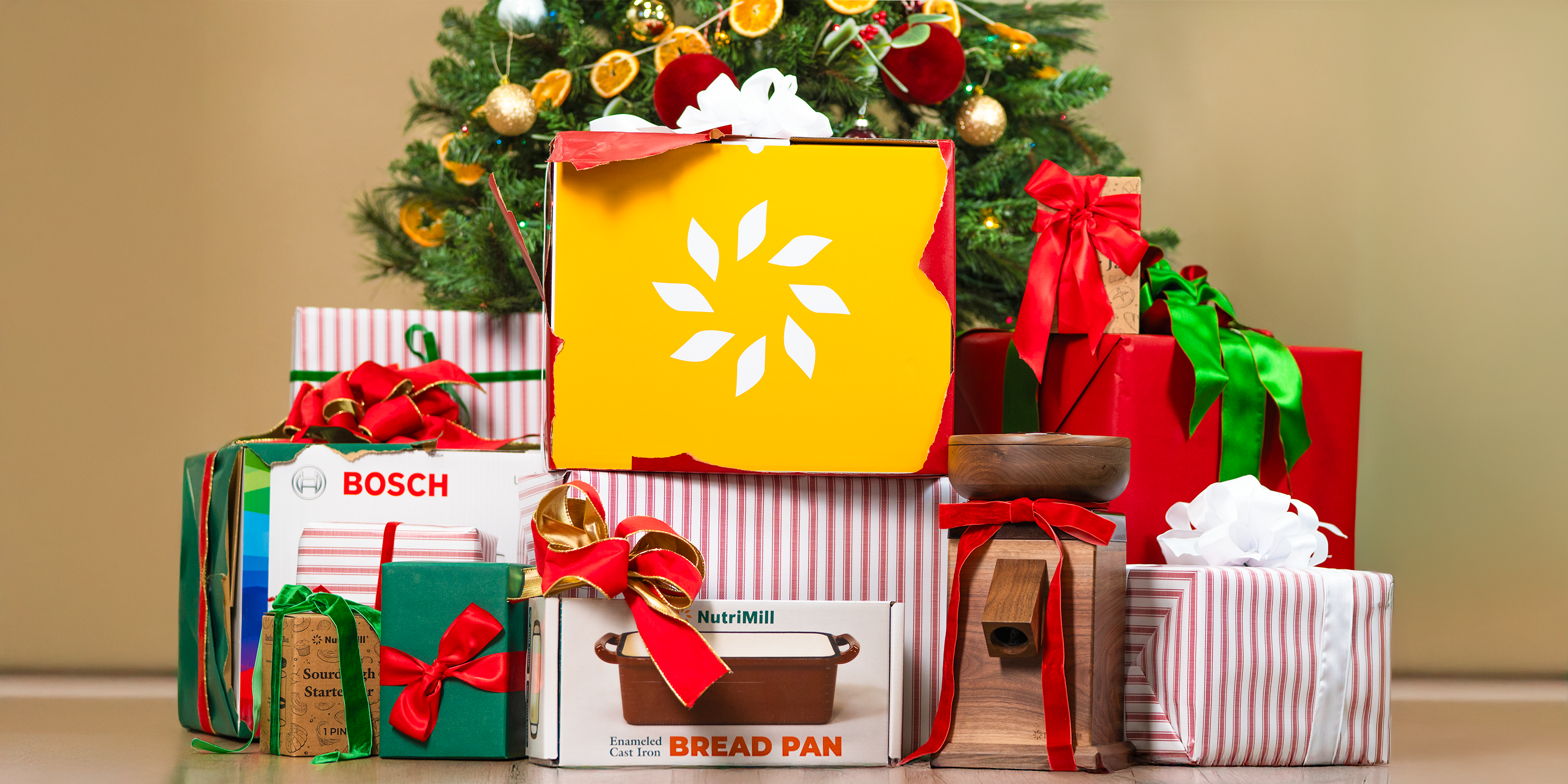 Different NutriMill kitchen products with bows and wrapping paper in front of Christmas tree