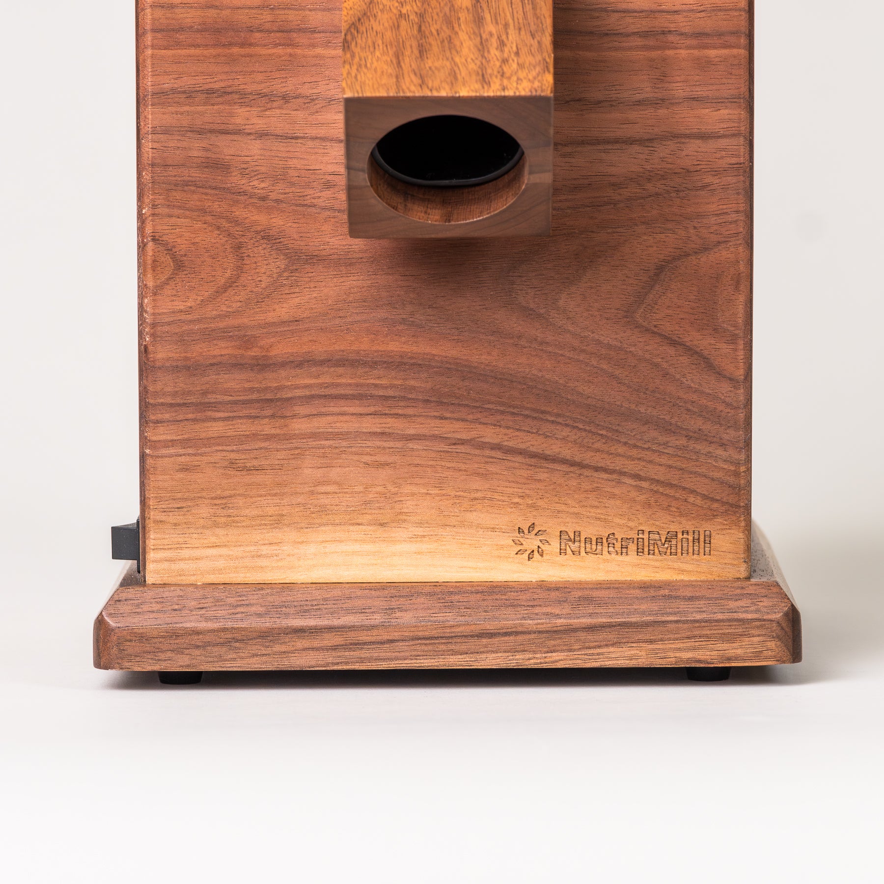 Close up of walnut harvest grain mill with NutriMill logo on grey background