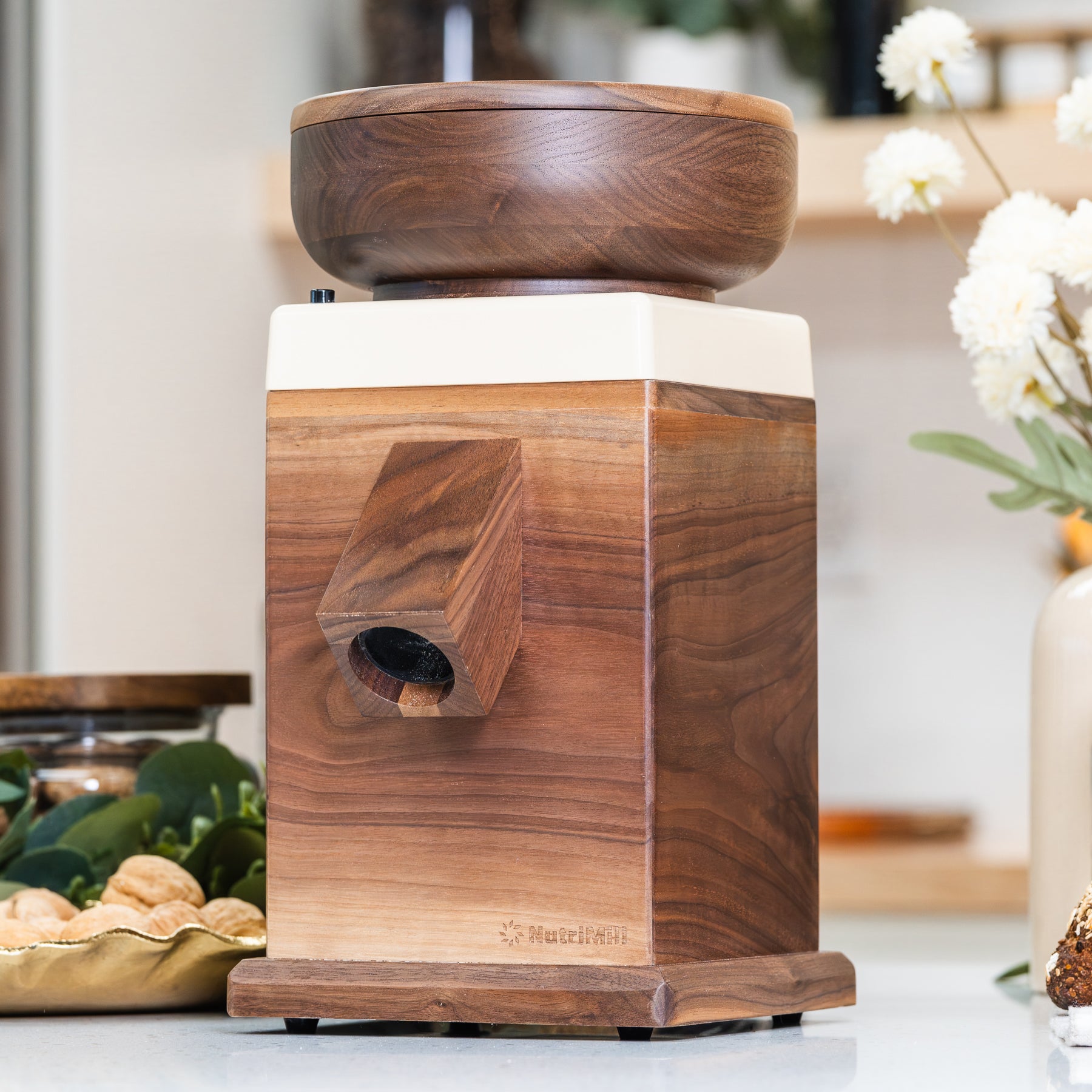 NutriMill harvest Walnut grain mill with cream-colored trim on white counter with kitchen in background