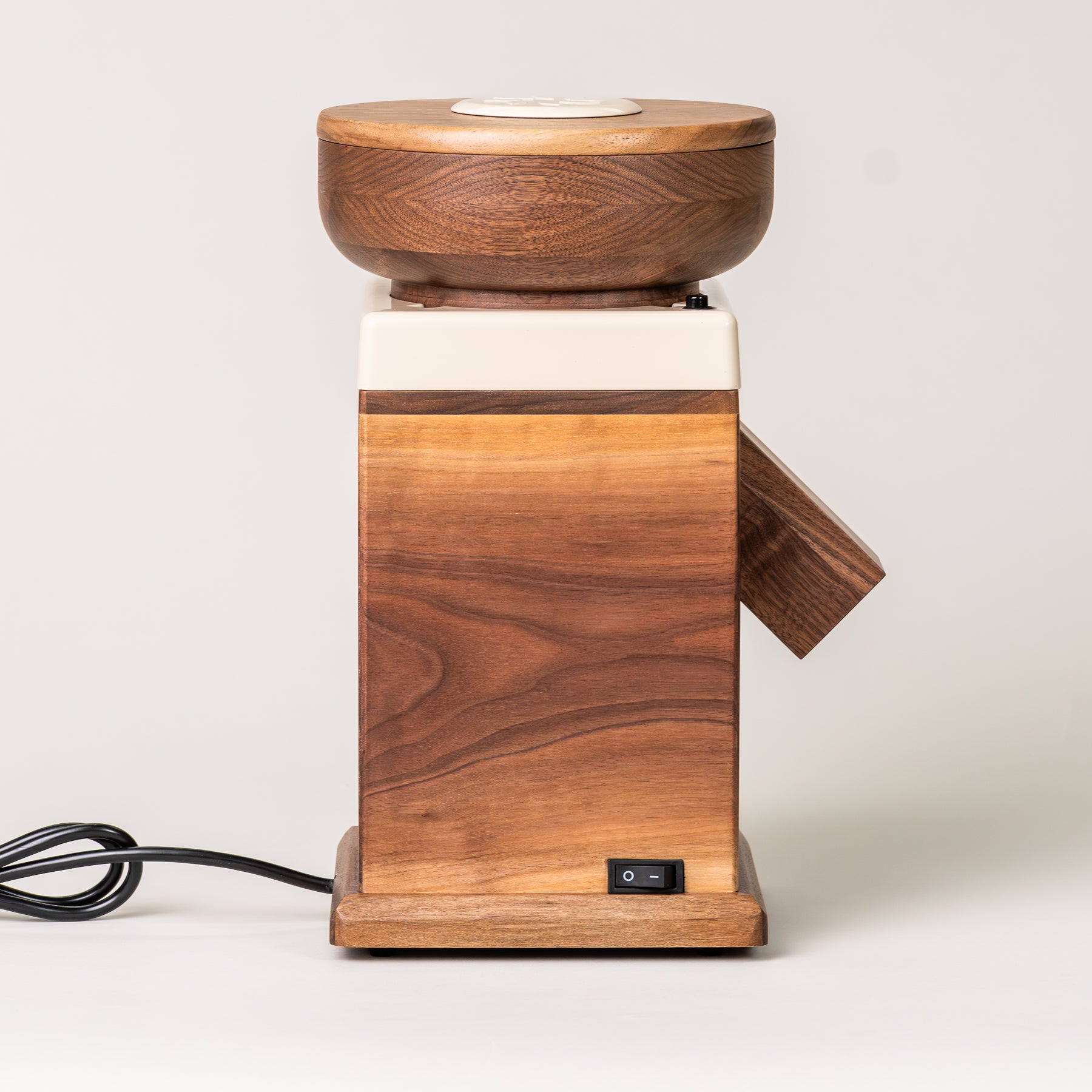 Side angle of NutriMill harvest walnut grain mill with cream-colored trim on grey background