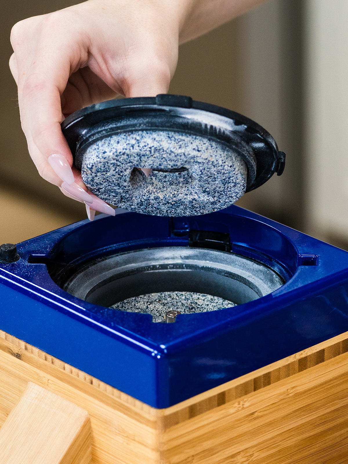 A woman changing the milling stones of a NutriMill harvest grain mill with a blue trim